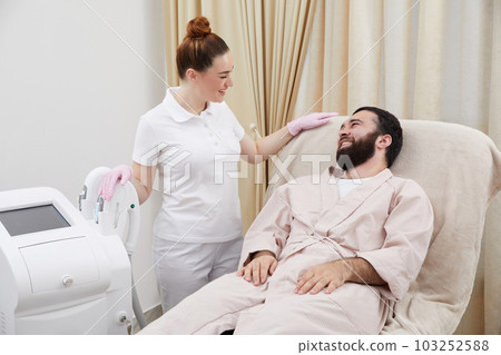 Consultation in cosmetology clinic. Female professional beauty doctor talking with pretty young men 103252588