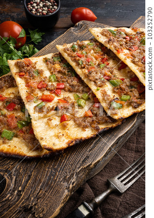 Kiymali pide Turkish pide with minced meat, on old dark wooden table background Kiymali pide Turkish pide with minced meat, on old dark wooden table background 103252790