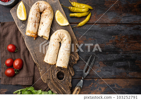 Tavuk tantuni durum Turkish cuisine doner kebab, on old dark wooden table background, top view flat lay, with copy space for text Tavuk tantuni durum Turkish cuisine doner kebab, on old dark wooden table background, top view flat lay, with copy space for text 103252791