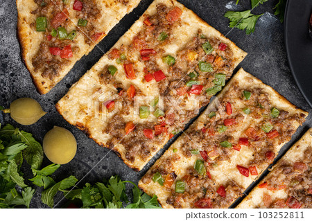 Dish pita precious Kiymali Pide, on black dark stone table background, top view flat lay Dish pita precious Kiymali Pide, on black dark stone table background, top view flat lay 103252811