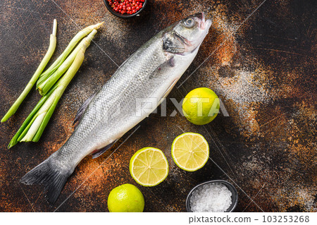 Raw sea bass with spices and herbs ingredients  over darc rustic background top view. 103253268