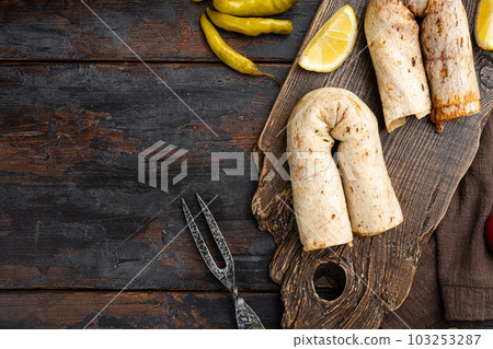 Doner kebab wrap in lavash bread, on old dark  wooden table background, top view flat lay, with copy space for text 103253287