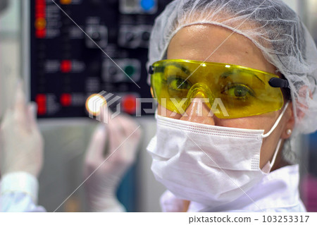 Portrait of Female Pharmaceutical Factory Worker Next to the Control Panel of Pharmaceutical Machine 103253317