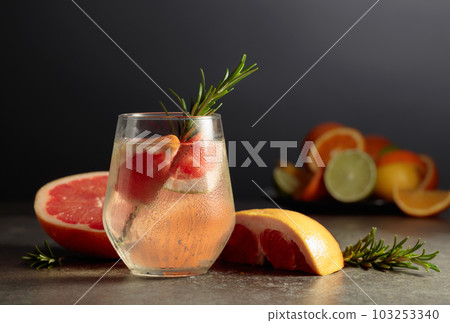 Cocktail gin tonic with ice, rosemary, and grapefruit on a stone table. 103253340