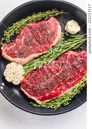Two raw picanha organic  beef steaks ready for grill on pan with herbs and garlic. Over white textured background, top view. 103253517