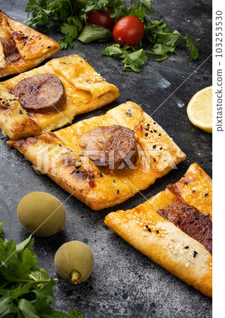 Sausage Pide or Sausage pizza Sucuklu Pide, on black dark stone table background 103253530