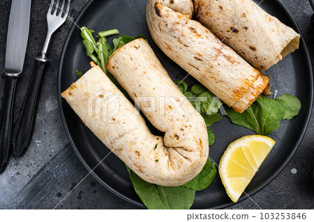 Tavuk tantuni durum Turkish cuisine doner kebab, on black dark stone table background, top view flat lay 103253846