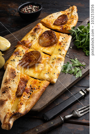 Turkish traditional sucuklu pide with pepperoni, on old dark  wooden table background 103253856