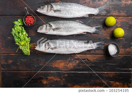 Fresh raw sea bass with spices and herbs ingredients on old fisherman dark wooden table top view. Fresh raw sea bass with spices and herbs ingredients on old fisherman dark wooden table top view. 103254195