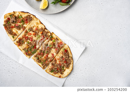 Turkish pide with minced lamb, tomatoes, bell pepper, on gray concrete table background, top view flat lay, with copy space for text 103254200