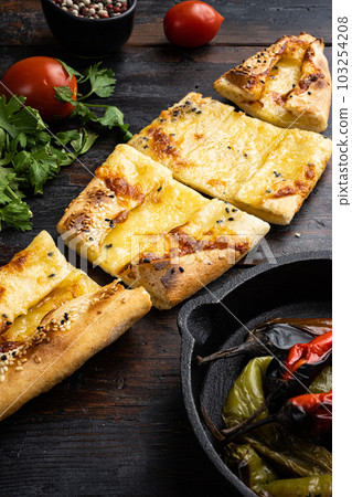 Peynirli pide,  pita with cheese and spinach, on old dark  wooden table background 103254208