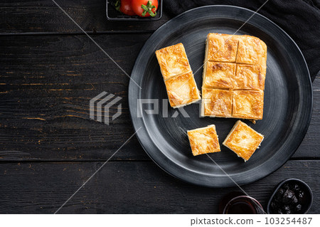Su Boregi pie, Turkish Tabla borek or burek, on black wooden table background, top view flat lay, with copy space for text Su Boregi pie, Turkish Tabla borek or burek, on black wooden table background, top view flat lay, with copy space for text 103254487