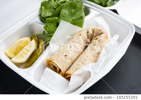 Turkish Style chicken roll Tavuk Durum tantuni, in plastic pack container delivery lunch box, on black dark stone table background Turkish Style chicken roll Tavuk Durum tantuni, in plastic pack container delivery lunch box, on black dark stone table background 103255291