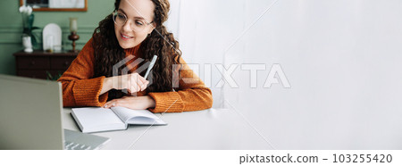 Young smiling pretty woman student using laptop elearning or remote working at home office using Young smiling pretty woman student using laptop elearning or remote working at home office using 103255420