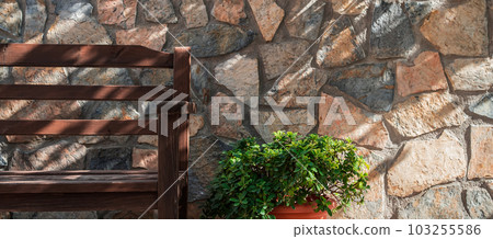 Empty wooden bench on wall background, yard or patio space decoration detail, shadows from tree crowns on the wall Empty wooden bench on wall background, yard or patio space decoration detail, shadows from tree crowns on the wall 103255586