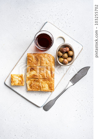 Turkish style meat and cheese stuffed filo dough borek, on gray concrete table background, top view flat lay, with copy space for text Turkish style meat and cheese stuffed filo dough borek, on gray concrete table background, top view flat lay, with copy space for text 103255702