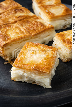 Delicious Turkish food Tray pastry with cheese, on black wooden table background Delicious Turkish food Tray pastry with cheese, on black wooden table background 103255707