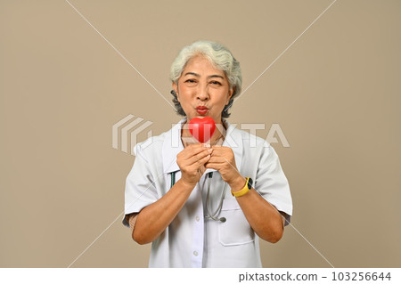 Portrait of senior female doctor cardiologist holding a red heart. Cardiology, medicine, donation and healthcare concept 103256644