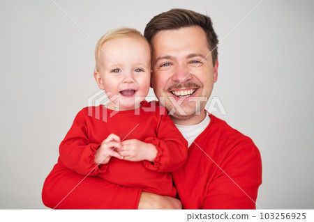 Happy father holding his baby daughter smiling at camera Happy father holding his baby daughter smiling at camera 103256925