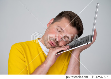 Tired caucasian man sleeping on a laptop having a nap time. Tired caucasian man sleeping on a laptop having a nap time. 103256926