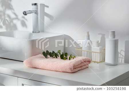 White cabinet displayed wash basin, folded towel and several unbranded pump bottles. Mockup bottle for skin care cosmetic. Natural soft shadow White cabinet displayed wash basin, folded towel and several unbranded pump bottles. Mockup bottle for skin care cosmetic. Natural soft shadow 103258198