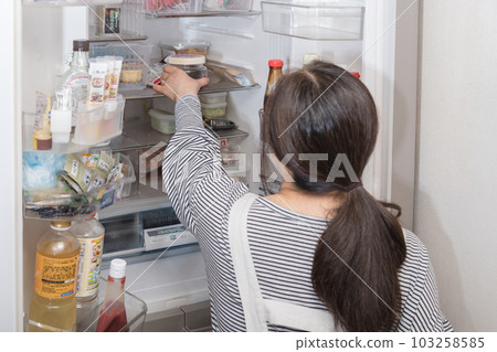 [一位家庭主婦從冰箱裡拿出一個酸梅] 103258585