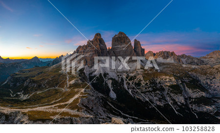 Edges of high peaks after sunset. Tre Chime di Lavaredo under a bright sky, an aerial view 103258828