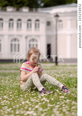 A girl sits in a meadow of flowers and smells a flower . High quality photo A girl sits in a meadow of flowers and smells a flower . High quality photo 103258932