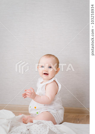 a pretty little girl in a white dress sitting on the floor, taking care of the baby. High quality photo a pretty little girl in a white dress sitting on the floor, taking care of the baby. High quality photo 103258934