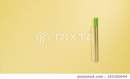 Metal straws for drinks and a brush for cleaning them on a yellow background Metal straws for drinks and a brush for cleaning them on a yellow background 103260044