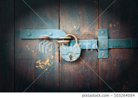 Old rusty padlock on a wooden door. Vintage camera effect on image 103264084