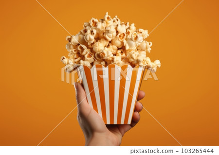 An image featuring hands holding a popcorn box, with popcorn kernels spilling out of the box. Concept irresistible nature of popcorn. Generative AI An image featuring hands holding a popcorn box, with popcorn kernels spilling out of the box. Concept irresistible nature of popcorn. Generative AI 103265444