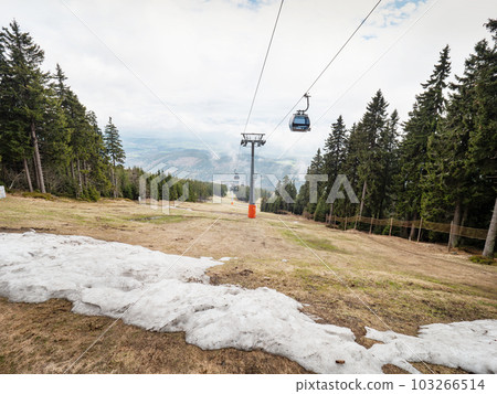 Cabin above grassy ski slope moving up to hill with tourist. 103266514