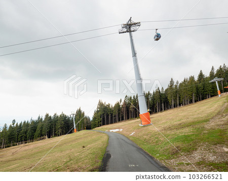 Cabin above grassy ski slope moving up to hill with tourist. 103266521