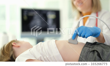 Doctor conducting abdominal ultrasound examination of internal organs of child in clinic closeup 103266773
