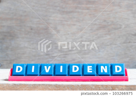 Tile alphabet letter with word dividend in red color rack on wood background Tile alphabet letter with word dividend in red color rack on wood background 103266975