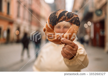 Senior woman holding prezel, traditional polish snack on the Market square in Krakow Senior woman holding prezel, traditional polish snack on the Market square in Krakow 103268327