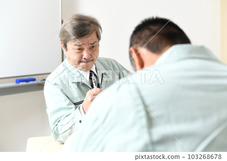 一個穿著工作服的中年男人正在關注他的下屬 103268678