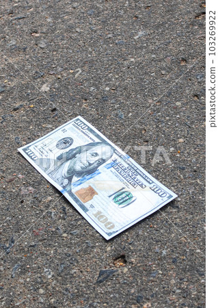 Crumpled one hundred dollar bill on pavement Crumpled one hundred dollar bill on pavement 103269922