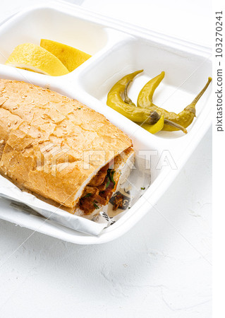 Chicken tantuni kebab Somun ekmek tavuk, in plastic pack container delivery lunch box, on white stone table background Chicken tantuni kebab Somun ekmek tavuk, in plastic pack container delivery lunch box, on white stone table background 103270241