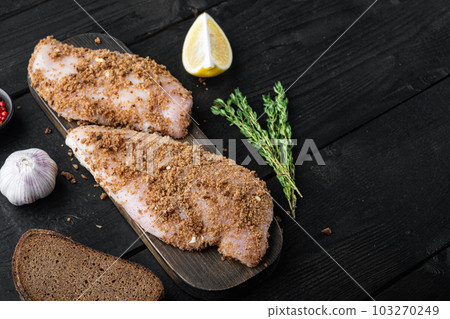 Raw crumbet chicken fillet with ingredients, on black wooden background  with copy space 103270249