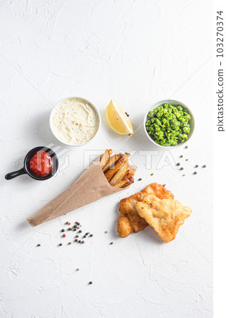 Components of traditional british set of fish and chips beer battered cod fillet, fries , lemon slices, tartar sauce and mushy peas , tomato ketcup for choice over white concrete background top view Components of traditional british set of fish and chips beer battered cod fillet, fries , lemon slices, tartar sauce and mushy peas , tomato ketcup for choice over white concrete background top view 103270374