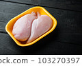 Raw chicken breast fillet in tray, on black wooden table with copy space for text 103270397