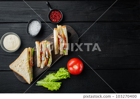 Club sandwich with meat, cheese, tomato, ham, on black wooden background, top view with copy space for text 103270400