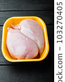 Raw chicken breast fillet in tray, on black wooden table 103270405