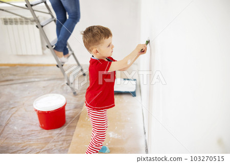 Mother and child son paint the wall with paint using roller and brush 103270515