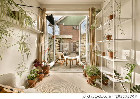 a living room with plants on the wall and an open door leading to a patio area in the back yard 103270707