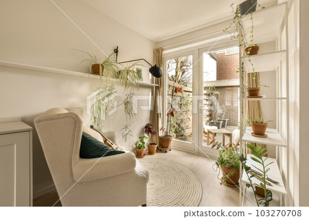 a living room with plants on the wall, and a chair in the corner by the door to the patio a living room with plants on the wall, and a chair in the corner by the door to the patio 103270708