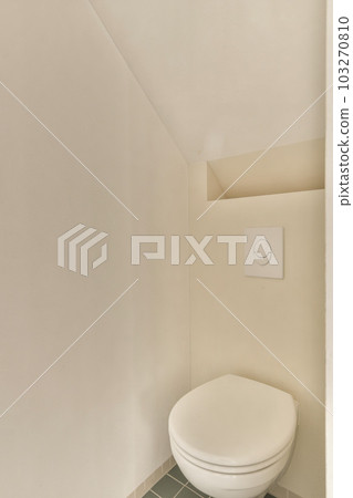 a toilet in the corner of a room with white walls and green tiles on the floor, there is an electrical outlet 103270810