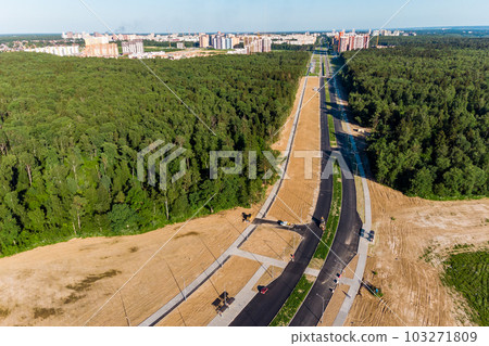 Aerial view of the road under construction leading to the city through the forest 103271809